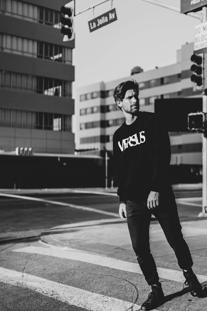 Stylish man in black outfit poses confidently at Los Angeles intersection, capturing urban street style.