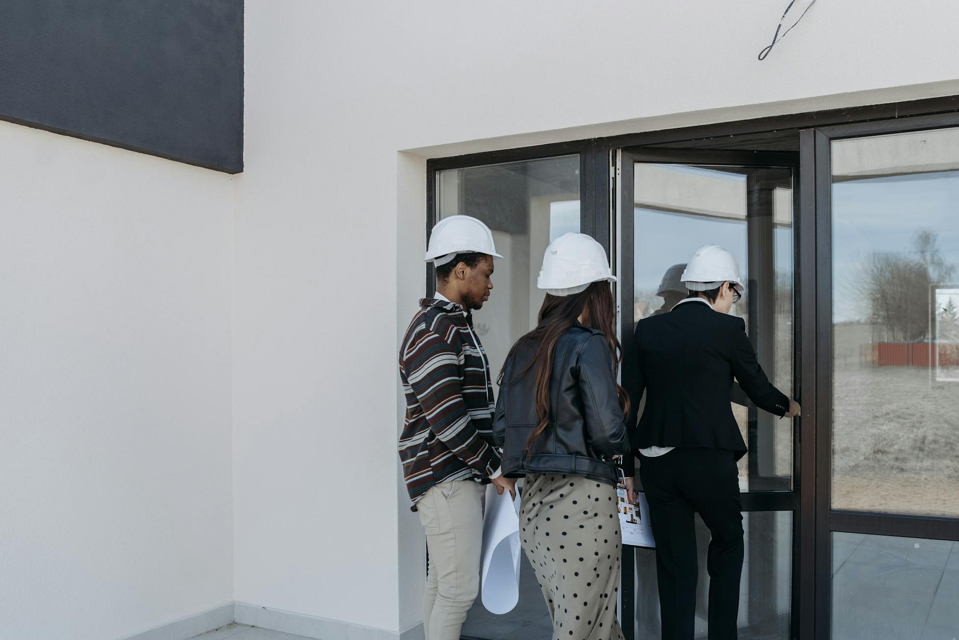 A group of diverse clients with a realtor at a new construction site entrance.