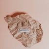 A crumpled brown paper on a pink background with the word 'thoughts' in focus.