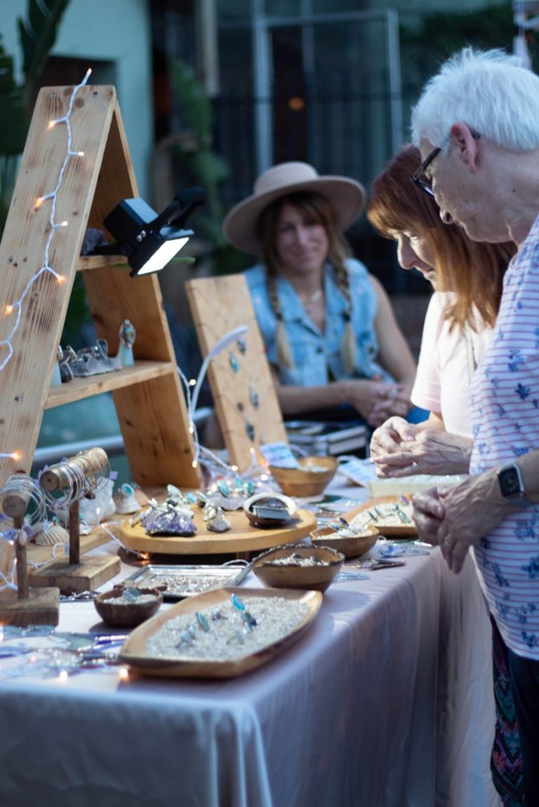 Shoppers browse handcrafted jewelry at an outdoor artisan market stall.