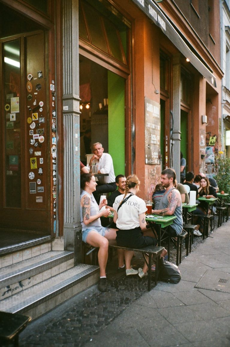 Group of friends enjoying a meal at an outdoor cafe on a city sidewalk.