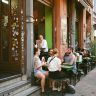 Group of friends enjoying a meal at an outdoor cafe on a city sidewalk.