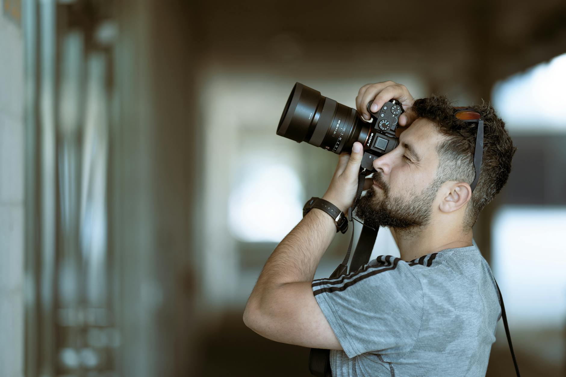 A focused photographer taking a photo with precision indoors, wearing casual attire.