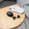 Close-up of modern gadgets: wireless earphones and a smartphone on a sleek wooden table.