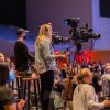 Side view of operators with cameras recording video during performance in concert room