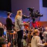 Side view of operators with cameras recording video during performance in concert room