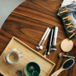 Stylish flatlay featuring makeup brushes, a Vogue magazine, and a coffee cup on a wooden table.